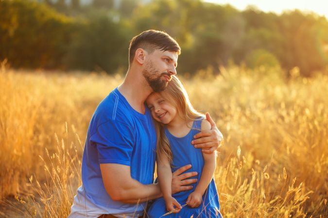 Dad and daughter child together in field of long grass