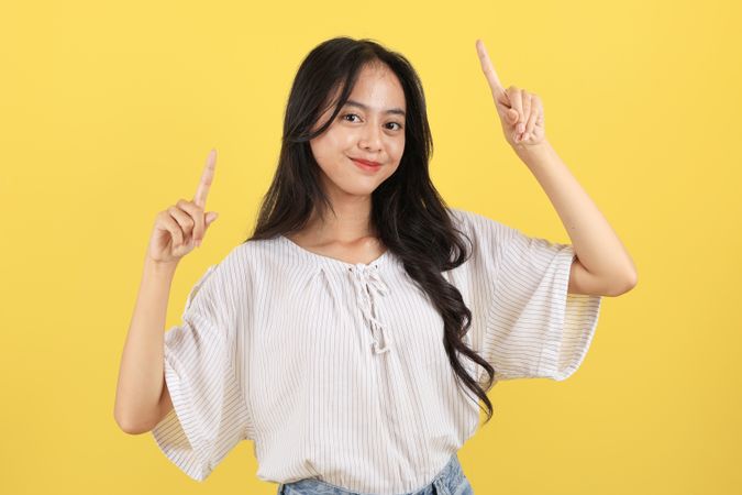 Portrait of Cheerful Asian Teenager with Long Hair and Casual Fashion, Pointing on Top for Advertisement
