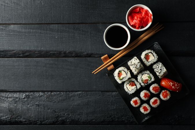 Tray with delicious sushi rolls on wooden background, top view. Japanese food