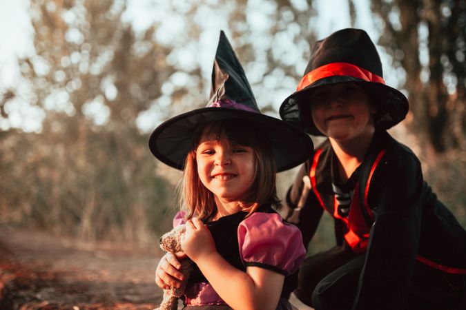 Happy brother and sister in halloween costumes in the forest