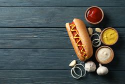Tasty hot dog and ingredients on wooden background