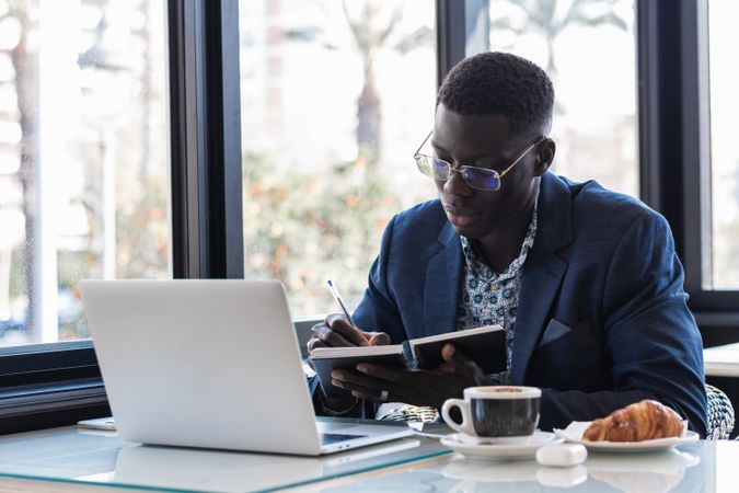 Focused Black male entrepreneur taking notes during work in cafe