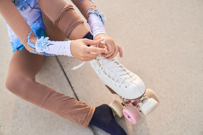 Unrecognizable person tying shoelaces on roller skate