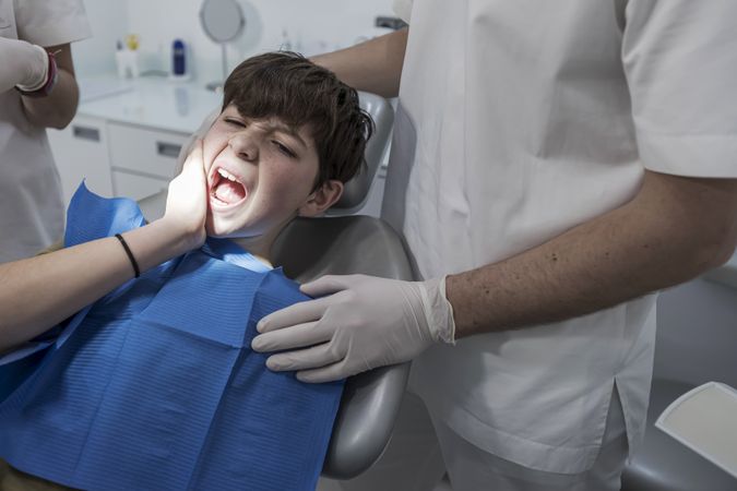 Teenage boy with tooth pain sitting in dental chair
