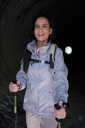 Cheerful Hispanic female hiker in dark tunnel