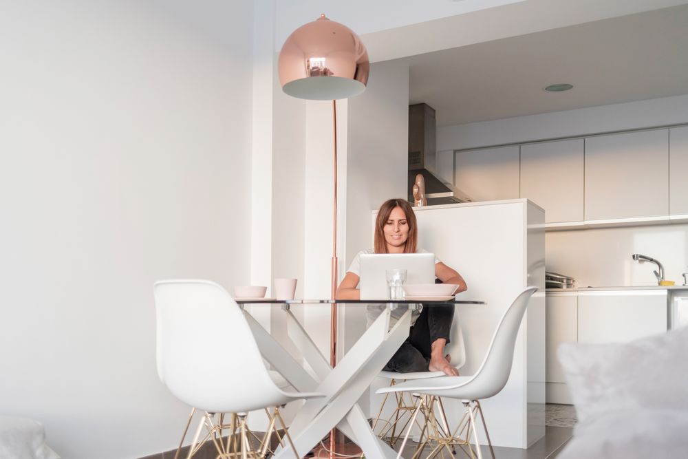 Female sitting at sunny breakfast table using her laptop