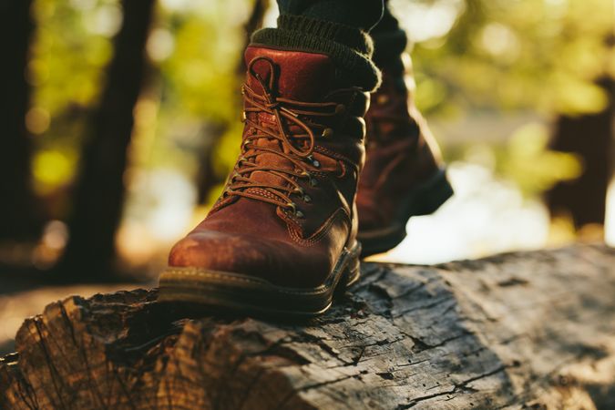 Close up of persons legs standing on a wooden log outdoors