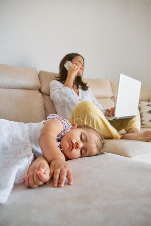 Baby sleeping near mother working remotely at home