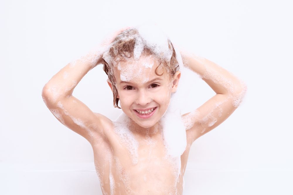 Smiling boy washing hair in bathroom