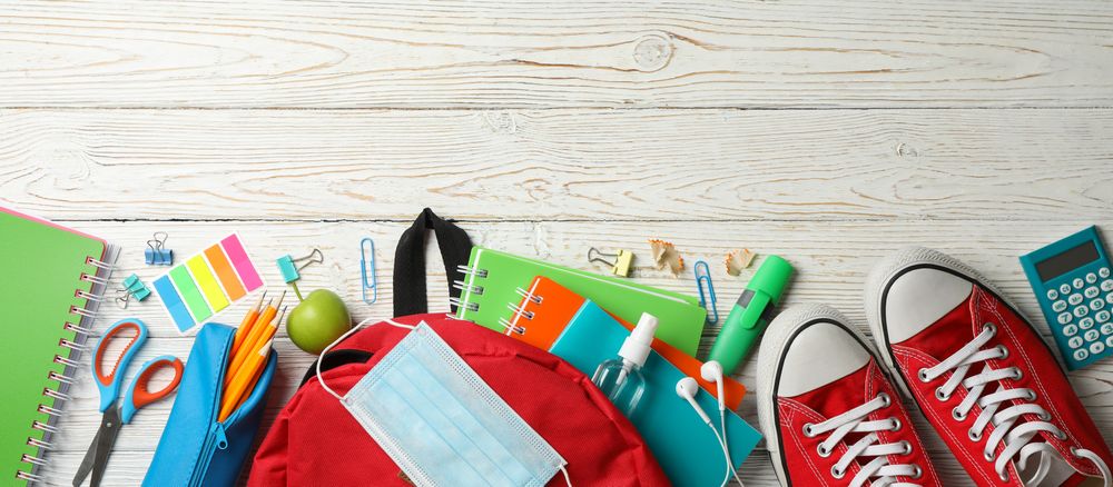 School supplies with medical mask and sanitizer on wooden background