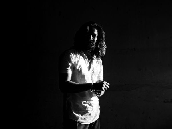 Grayscale photo of man in light shirt standing in dark room