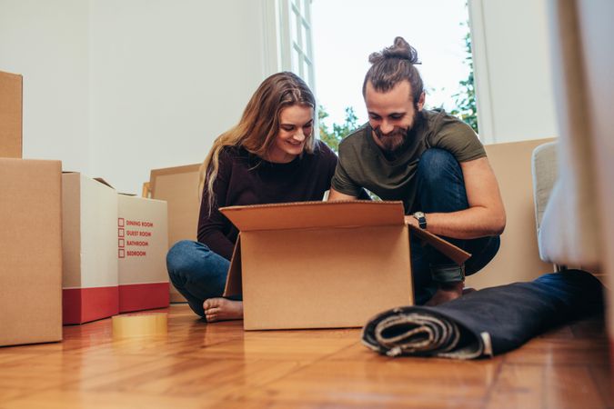 Happy couple opening their items after moving in a new home
