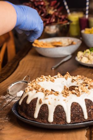 Chef adding nuts on top of frosted cake
