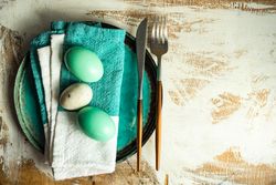 Top view of Easter table setting with ceramic teal plates and Easter eggs