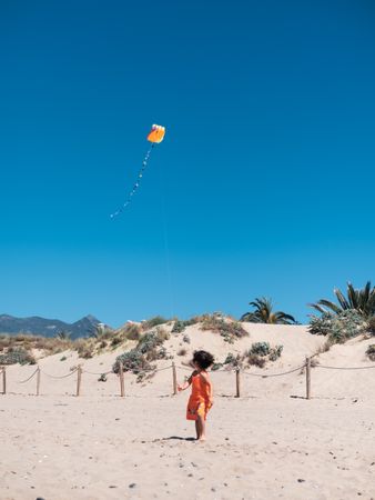 Toddler girl playing with kite on sandy beach