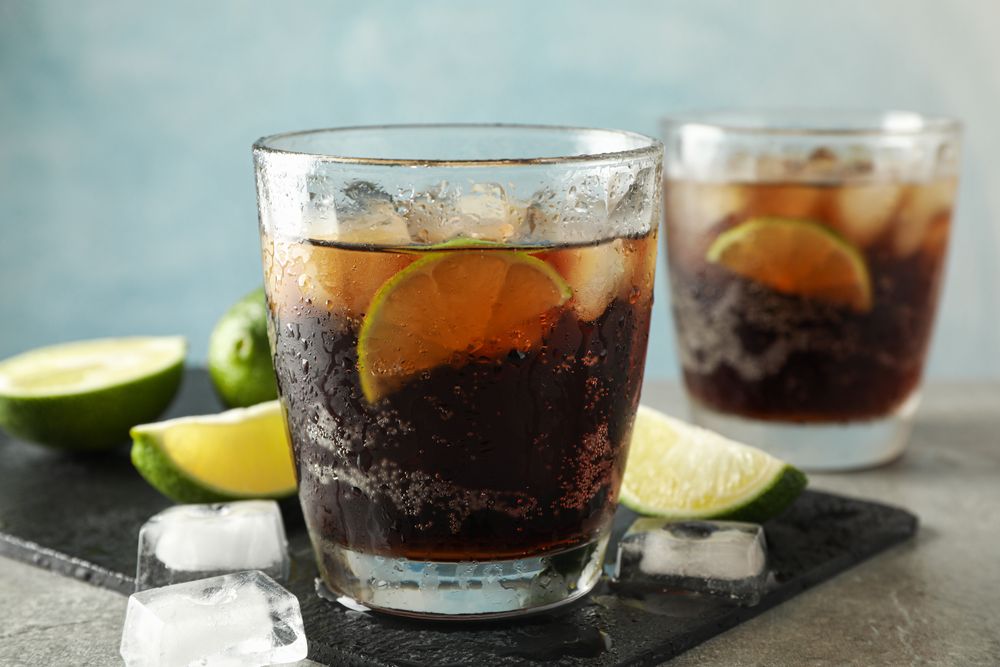 Glasses with cold cola and citrus on grey table, space for text