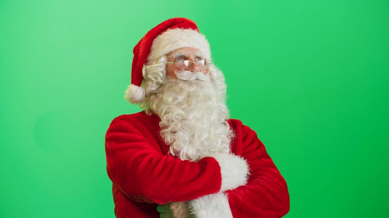 Studio Shot Isolated Mockup Template: Jolly Santa Claus Standing On Green Screen Chromakey Background With Hands Crossed, Looks At the Camera. Christmas, New Year, Holiday Celebration