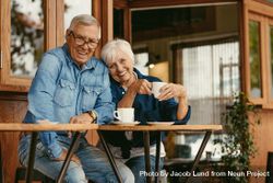Beautiful portrait of a man and woman sitting at cafe table with coffee looking at camera 5ogq15
