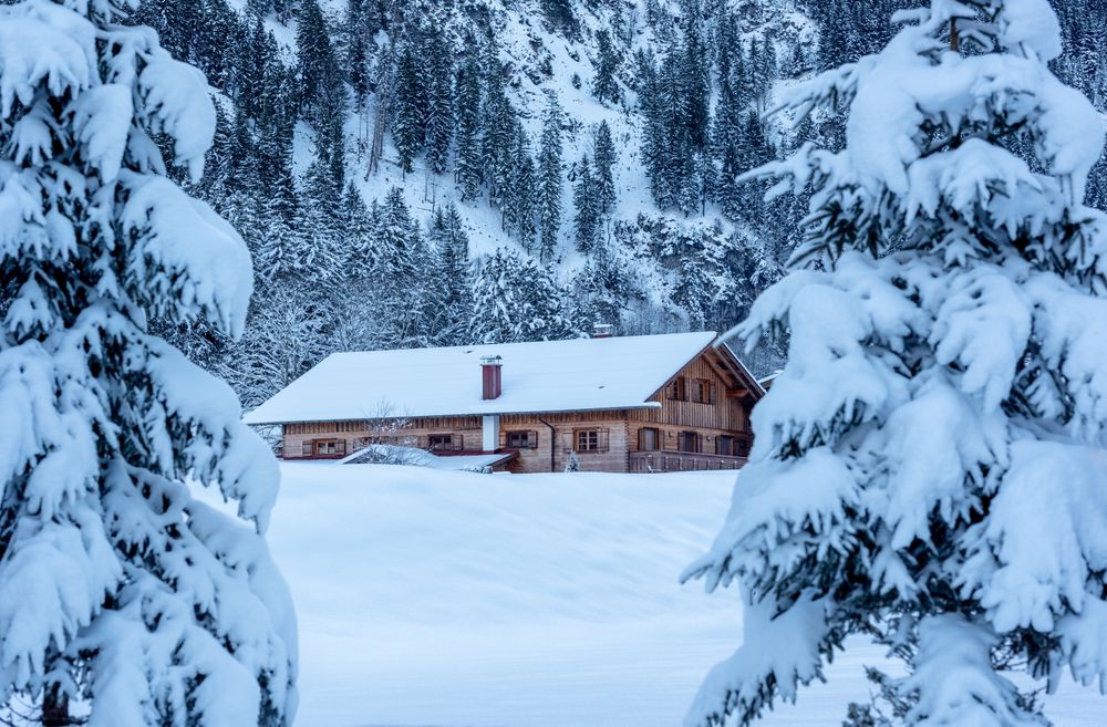 Winter landscape with snow-covered nature and log cabin in the Bavarian Alps, Germany