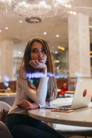 Female student rests her chin in her hand at her restaurant table