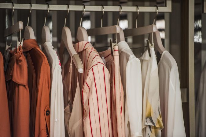 Pink and brown and light shirts on a clothing rack in fashion store