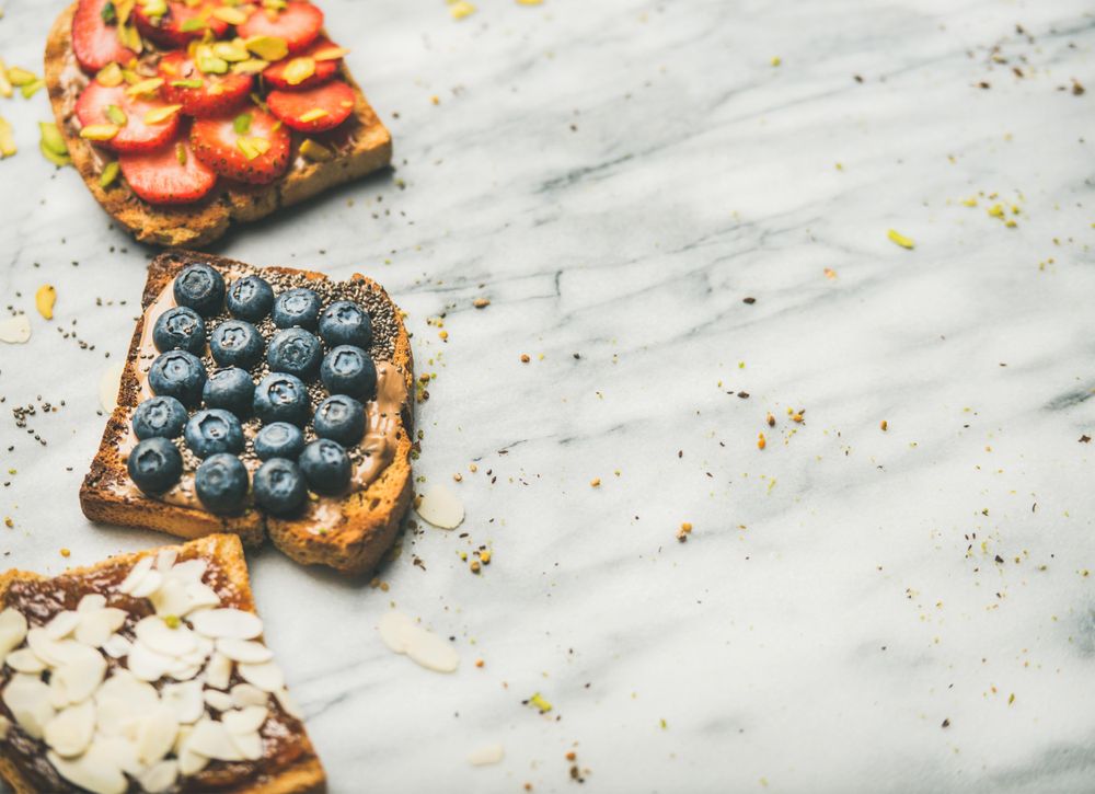 Toast topped with fresh fruit on marble background, horizontal composition with copy space