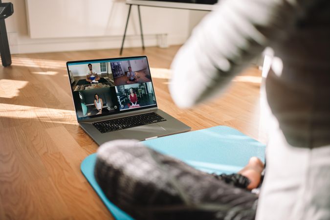 View of a woman conducting virtual fitness class with group of people at home on a video conference