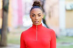 Female in red zipped up shirt standing outside