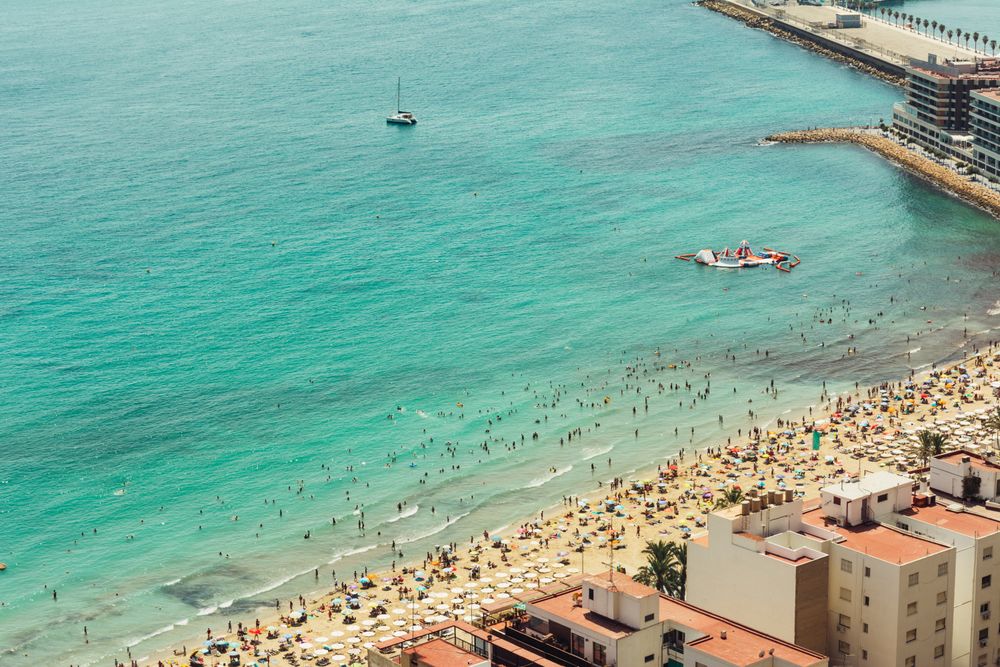 Stunning turquoise water and seashore with people palms boats