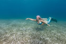 Blond fairytale female mermaid swimming underwater