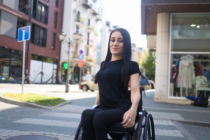 Happy woman in wheelchair on crosswalk