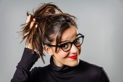 Woman with glasses and red lips touching her hair bun