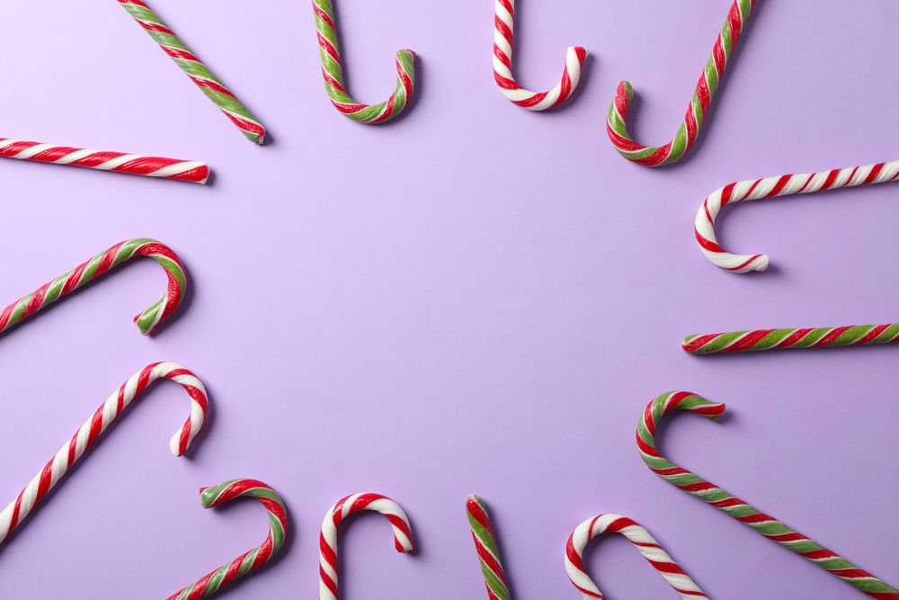Composition with sweet candy canes on color background, space for text