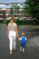 Unrecognizable woman and boy with backpack walking on street