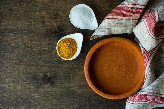 Spices on rustic background with terracotta bowl on wooden table