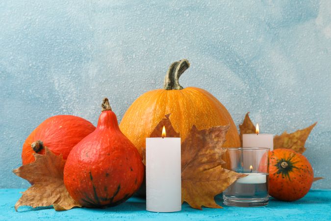 Composition with pumpkins and candles on wooden background, space for text