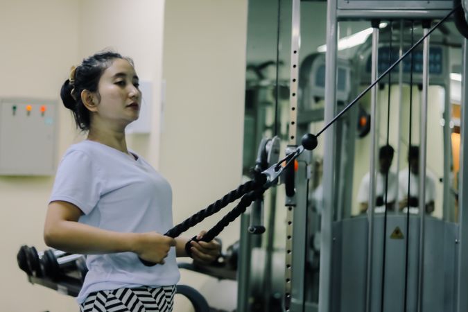 A woman using a cable machine At the gym
