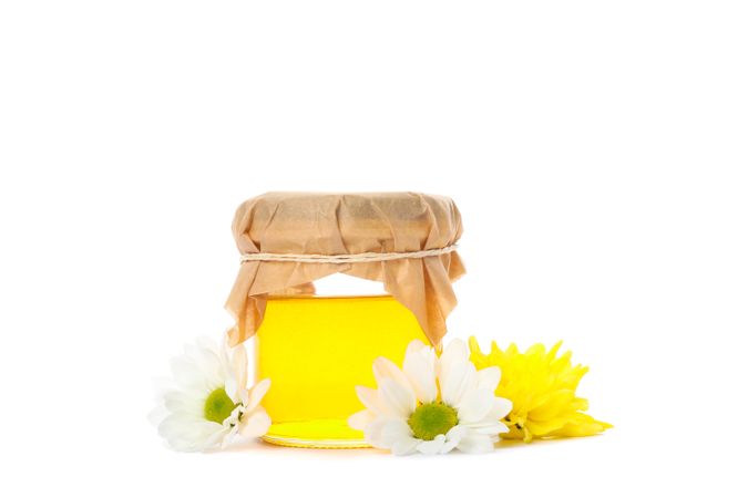 Glass jar with honey, chrysanthemum and chamomile isolated on plain background