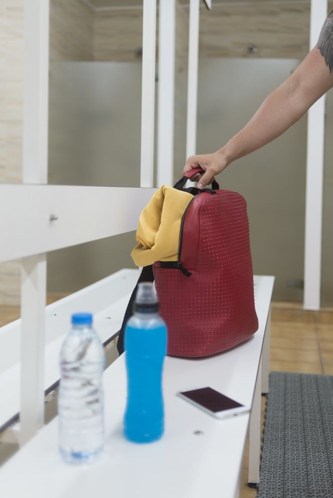 Male arm with his items in shower room on bench