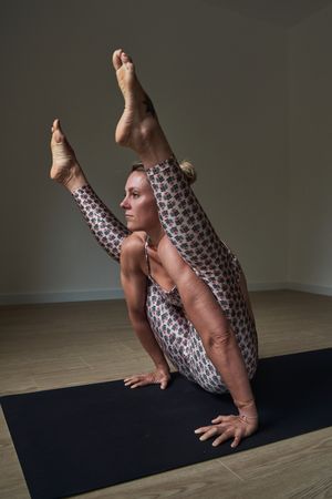 Woman practicing yoga in Firefly pose at home