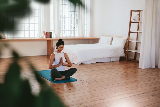 Relaxed woman meditating in lotus pose on yoga mat