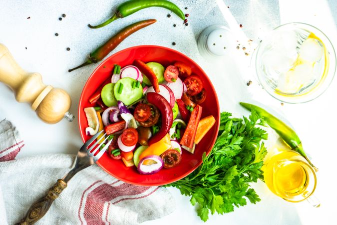 Top view of colorful healthy raw vegetable salad served in red bowl with copy space