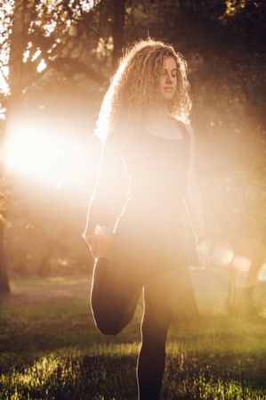 Sportive woman standing on meadow in sunlight