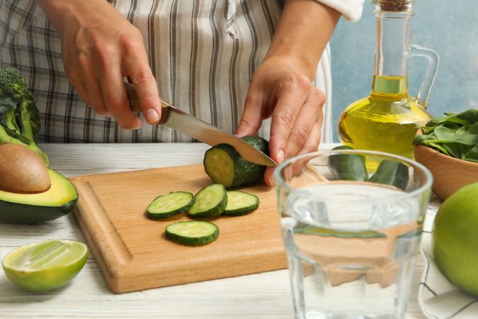 Woman cutted cucumber on wooden table