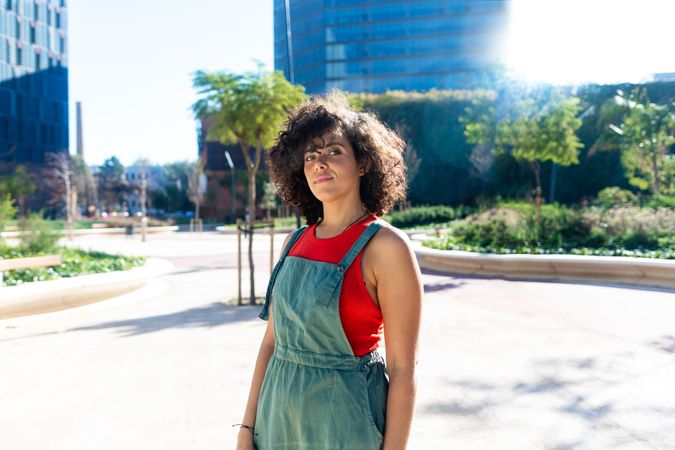 Woman standing on street in red vest and coveralls