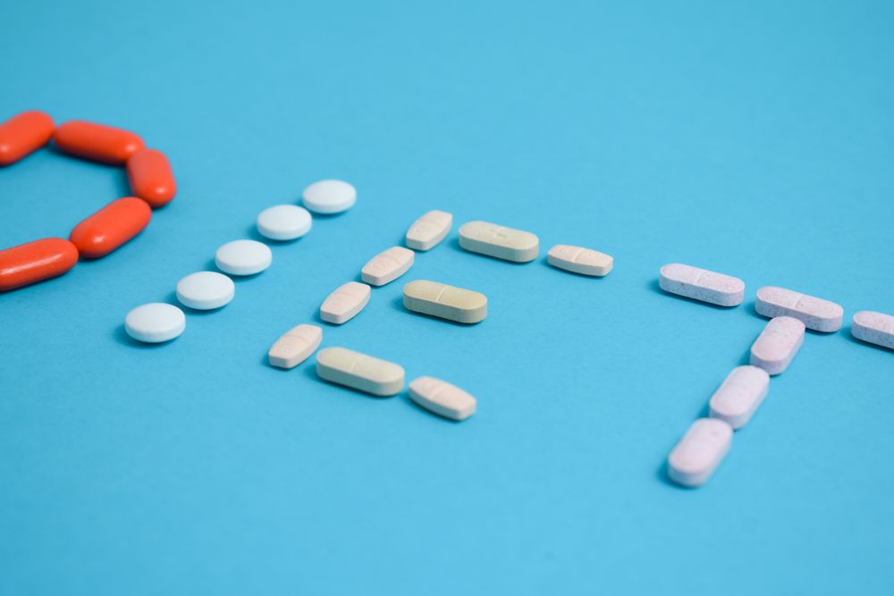 Multiple pills spelling the word "DIET" on blue background