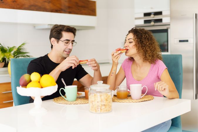 Couple eating delicious breakfast in bright kitchen