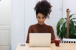 Black woman working on laptop in cafe