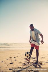 Young man kicking soccer football at the seaside 4mdQd5