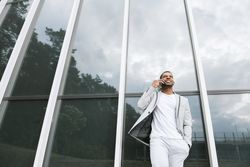 Elegant Black man talking smartphone leaning building
